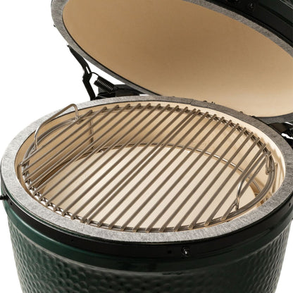 Close-up of a ceramic kamado grill with the lid open, showing a metal grill grate resting on a light beige ceramic interior against a white background.