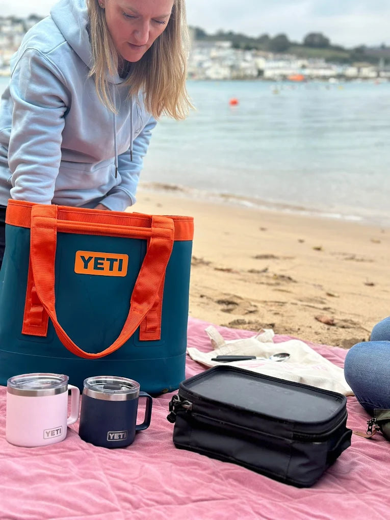 Person with a YETI cooler and accessories on a beach