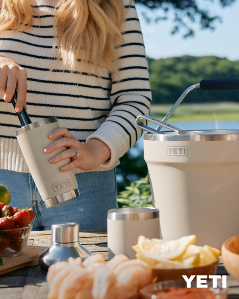 Person holding a YETI insulated cup outdoors with a scenic background